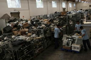 Employees push a cart loaded with discarded electronic products at the Coopermiti warehouse in Sao Paulo